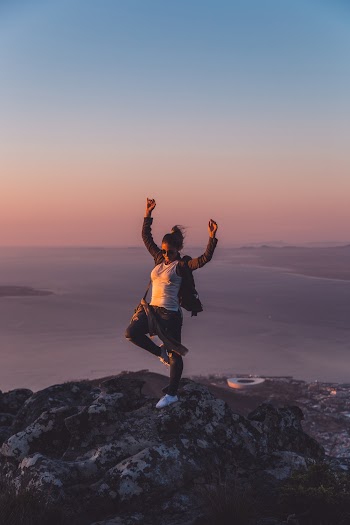 Woman With Hands Up Standing On Rock