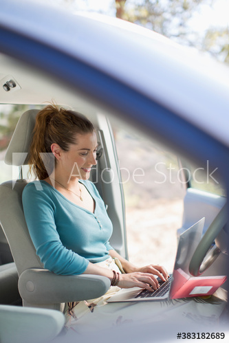 Woman with laptop working inside car