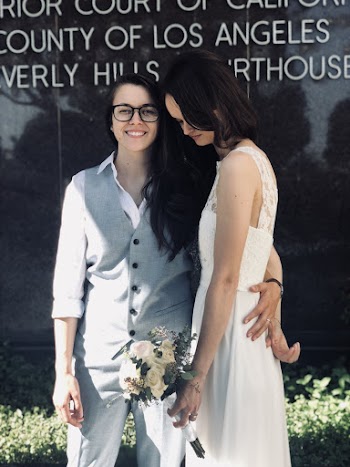 Woman With Left Arm Behind Woman's Back in Front of Black Wall