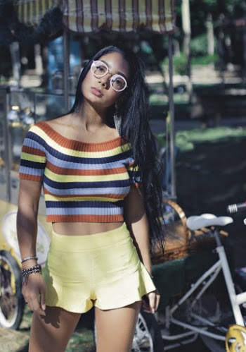 Woman with long black hair wearing Striped Colorful top and Yellow Shorts