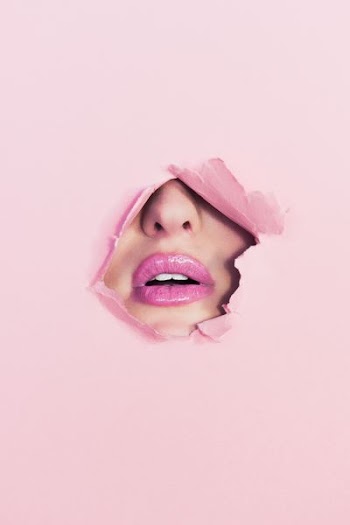 woman with pink lipstick on hole of pink paper