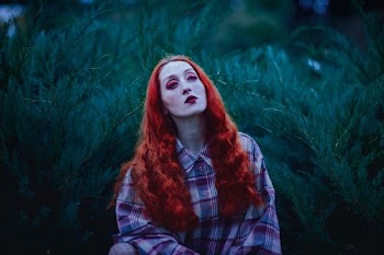 woman with red hair and red lipstick near green leafed plants