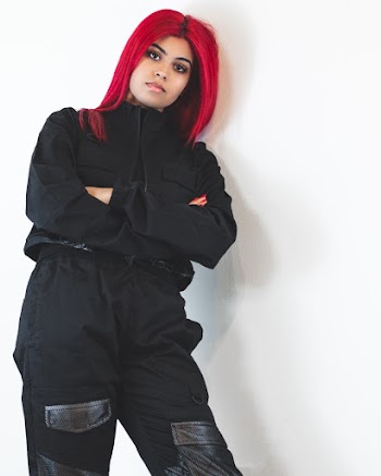 Woman with Red Hair In Black Outfit Leaning on wall