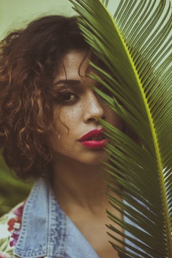 Woman With Red Lipstick Covering Face With Green Fern Plant
