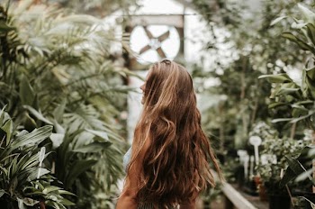 woman with strawberry blonde hair walking in the middle of green plants