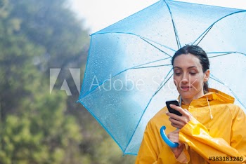 Woman with umbrella using smart phone in rain