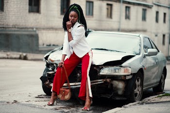 Woman With White Long-sleeved Shirt, Red ,and White Slit Pants and Pair of Black Open-toe D'orsay Heel Sandals Sitting on Wrecked Silver Car