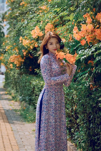 Women's Blue, White, and Purple Long-sleeved Maxi Dress Standing Beside Orange Flowers