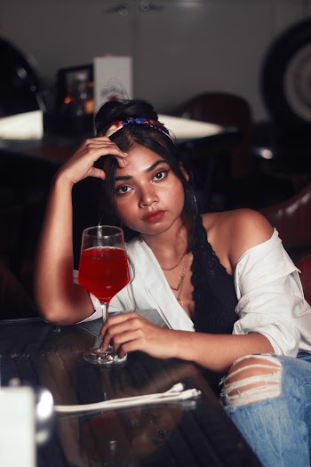 Women's Holding a Wine Glass While Sitting on the Chair Near Table