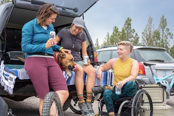 Women Drinking Beer Behind a Truck While Petting a Dog