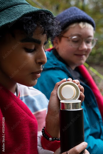 Women drinking from insulated drink container while camping