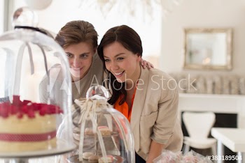 Women friends eyeing desserts in bakery