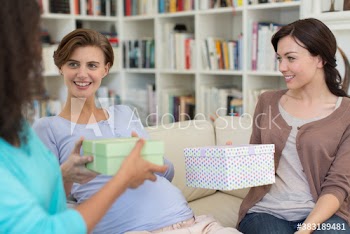 Women giving pregnant friend gifts at baby shower