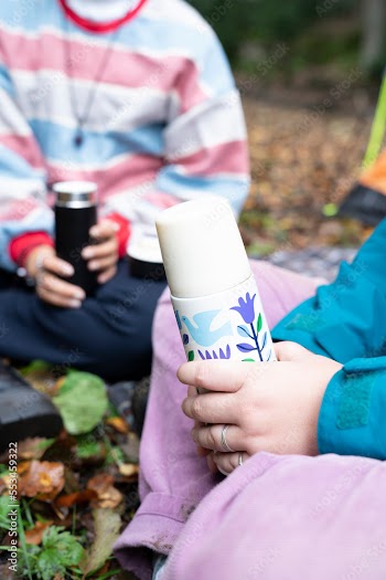 Women holding insulated drink containers while camping