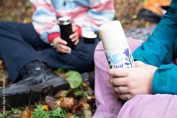 Women holding insulated drink containers while camping
