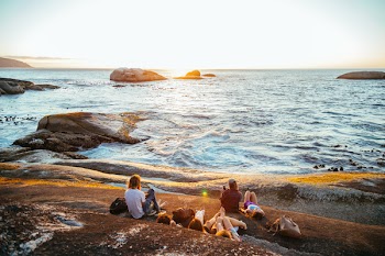 Women Sitting and Laying in Front of Body of Water