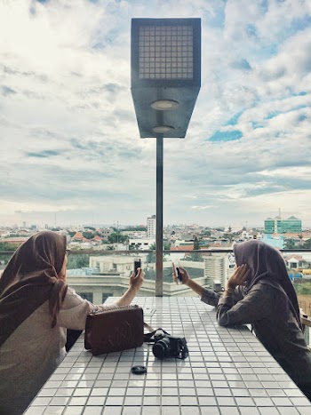 Women Sitting In Front Of Table While Holding Smartphones
