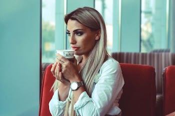 women sitting on chair holding cup of coffee