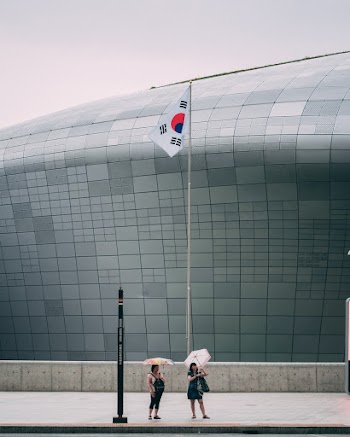 Women Standing Under Flag In Front Of A Building