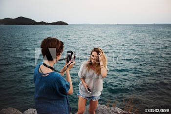 Women taking photo by seashore