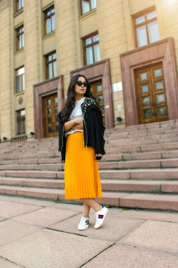 Women Wearing Black Jacket and Pleated Yellow Skirt Standing on Brown Floor