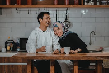 Women Wearing Hijab Leaning on a Man Near a Brown Table