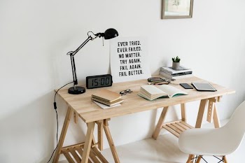 wooden desk with books and task lamp