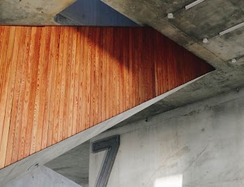 Wooden panelling on the side of a staircase in a building with bare concrete walls