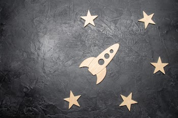 Wooden space rocket and stars on a dark background. The concept of...
