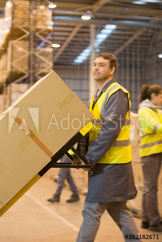 Worker moving boxes with hand truck in distribution warehouse
