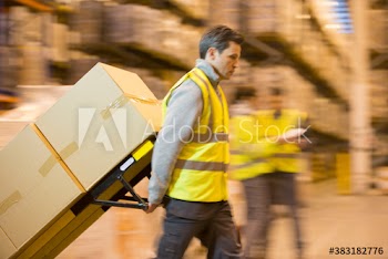 Worker moving boxes with hand truck in distribution warehouse
