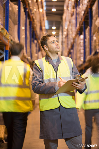 Worker with clipboard checking inventory in distribution warehouse