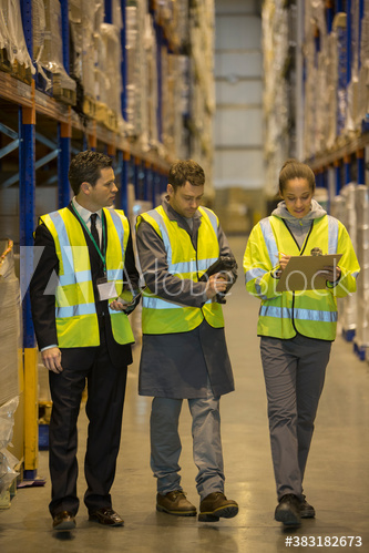 Workers and manager in aisle of distribution warehouse