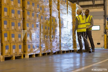 Workers examining pallets of boxes in distribution warehouse