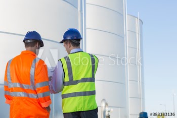 Workers meeting below steel storage tanks