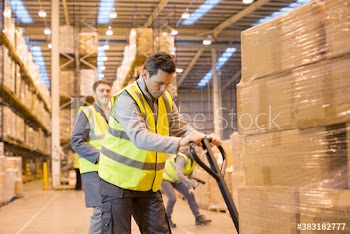 Workers moving boxes with pallet jack in distribution warehouse