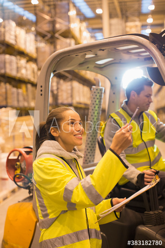 Workers talking at forklift in distribution warehouse