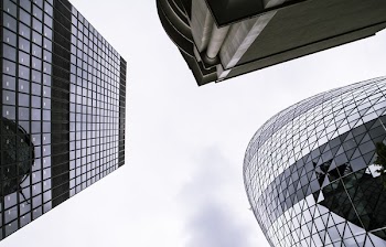 Worm's Eye View of Mirror Covered Concrete Buildings Under Gray Cloudy Skies