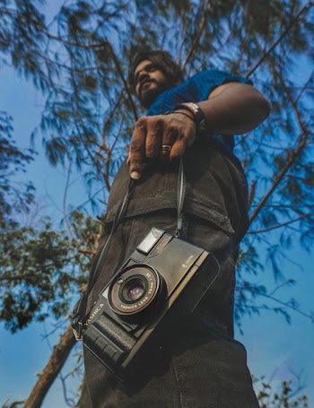 Worm's View of Man Holding Camera Under Blue Calm Sky