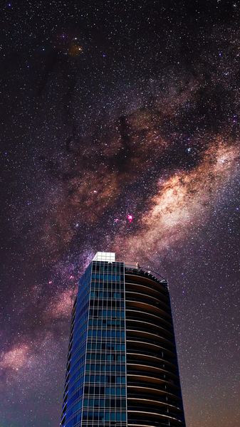 worm's-view photo of curtain wall building against galaxy
