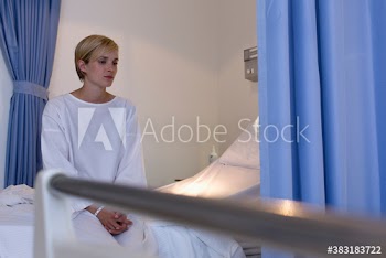 Worried female patient sitting on edge of hospital bed