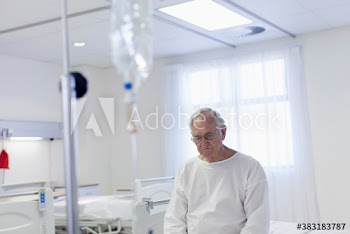Worried male senior patient sitting on edge of hospital bed