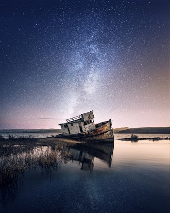 Wrecked Ship on Body of Water With Galaxy Background