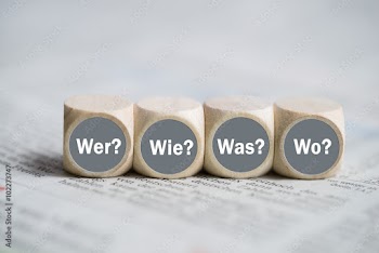 Würfel mit den Wörtern "Wer, Wie, Was und Wo" auf einer Zeitung