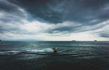 Yellow and Black Boat on Sea Under Gray Clouds