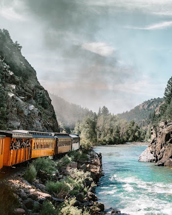 Yellow and Multicolored Train Near Body of Water