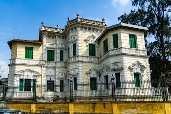 Yellow and White Painted Mansion Near Black Iron Gate