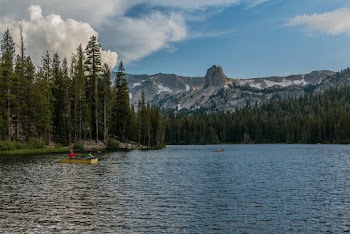 Yellow Boat on Body of Water Across Brown and White Mountain