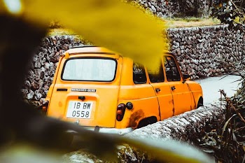 yellow car near stone wall at daytime
