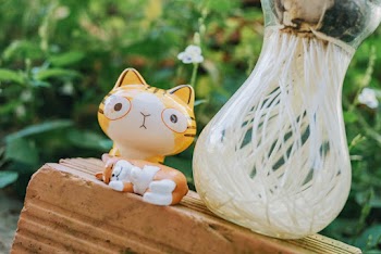 Yellow Cat Figurine Beside Clear Glass Vase